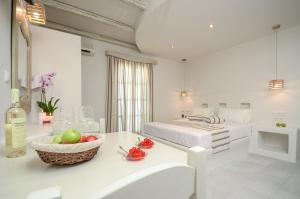 Cette chambre blanche comprend un lit et une corbeille de fruits sur une table. dans l'établissement Agnadi Hotel, à Agia Anna