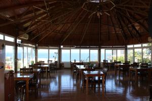 a dining room with tables and chairs and windows at Huzur Hotel in Siğacık
