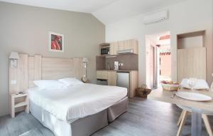 a bedroom with a large white bed and a kitchen at Résidence Odalys Le Village Camarguais Les Gardians in Arles