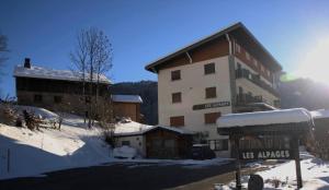 a large building in the snow next to a bus stop at 65m2 - balcon et vue sur les Aravis in La Giettaz