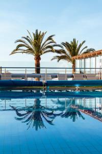 une piscine avec des palmiers en arrière-plan dans l'établissement Christina Beach Hotel, à La Canée