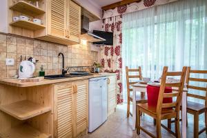 eine Küche mit Holzschränken sowie einem Tisch und Stühlen in der Unterkunft Aparthotel Pod Nosalem in Zakopane