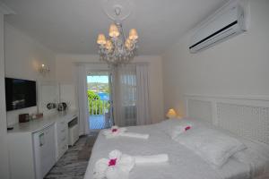 um quarto com uma cama branca com flores nas almofadas em Karianda Hotel em Golturkbuku