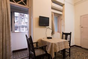 a dining room with a table and a tv on the wall at Bed and Breakfast at Colaba in Mumbai