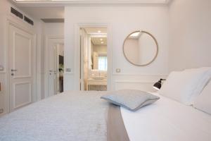 a white bedroom with a bed and a mirror at Hotel Majestic in Budva