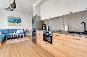 uma cozinha com armários brancos e um sofá azul em Amber Baltic Apartment em Gdansk