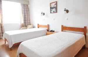 a hotel room with two beds and a window at Hotel São Francisco in Horta