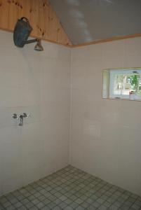 a tiled bathroom with a fan and a window at Hallikivi Tourist Farm in Vennarti