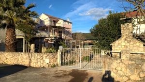 a fence in front of a house with a palm tree at Captain Apartments in Vinišće