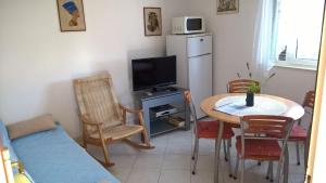 a kitchen with a table and a refrigerator and a table and chairs at Captain Apartments in Vinišće