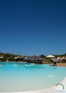 una gran piscina azul con sombrillas de fondo en Residence Hotel Monte Ricciu, en Alghero