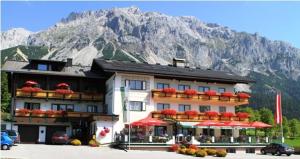 un edificio con ombrelloni rossi di fronte a una montagna di Der Brückenhof Ramsau a Ramsau am Dachstein
