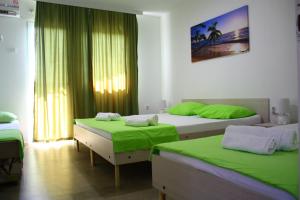 a bedroom with two beds with green sheets and a window at Apartments Villa Naumovi in Star Dojran