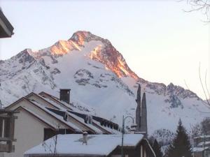 una montaña cubierta de nieve con el sol brillando sobre ella en Chalet Le Ranch, en Les Deux Alpes