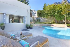 a swimming pool with chaise lounge chairs next to a house at Vetho Villa in Cape Town