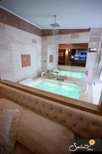 a large bathroom with a large tub with a green pool at Tesoretto Hotel in Poggiardo