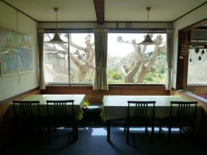 uma sala de jantar com duas mesas e uma janela em Pension Flora em Tateyama