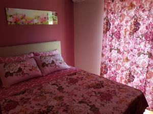 a pink bedroom with a bed with a pink floral curtain at Apartments Vila Galileo in Budva