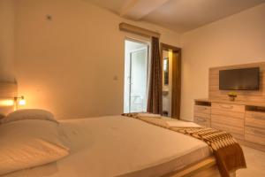 a bedroom with a bed and a flat screen tv at Guest House Maslina in Petrovac na Moru