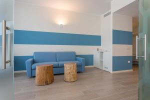 a living room with a blue couch and two logs at Hotel Mediterraneo in Sottomarina
