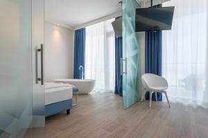 łazienka z wanną i telewizor w pokoju w obiekcie Hotel Mediterraneo w mieście Sottomarina