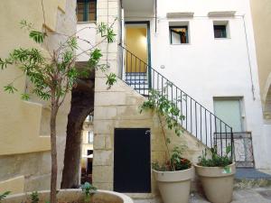 een gebouw met een zwarte deur en twee grote planten bij L'arco delle Commari in Ragusa