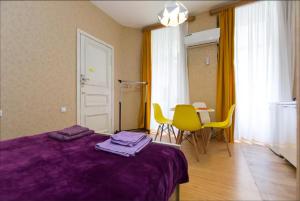- une chambre avec un lit violet, une table et des chaises dans l'établissement Pop Art Studio Apartment, à Tbilissi