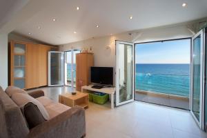 a living room with a couch and a television and the ocean at Infinity Beach House in Kefalonia in Argostoli