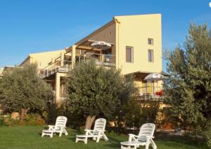 a group of lawn chairs in front of a building at Sorta Apartments in Kato Daratso