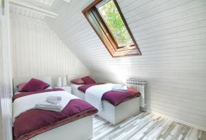 two beds in a attic room with a window at Estavela Holiday home in Jezerce