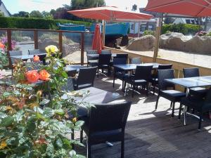 un patio avec des tables, des chaises et des parasols dans l'établissement Hotel Restaurant Le Phare, à Perros-Guirec