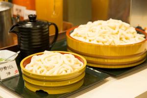 two stacks of noodles in yellow bowls on a counter at Sanco Inn Iseshi-Ekimae Shikinoyu in Ise