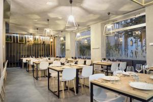 une salle à manger avec des tables et des chaises blanches dans l'établissement B&B Hotel Ljubljana Park, à Ljubljana