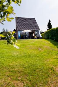Vlagtwedde的住宿－Hebrechthuis，绿色田野上黑色屋顶的房子