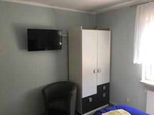 um quarto com uma televisão, um armário e uma cadeira em Möllis Apartment am Jasmund-Nationalpark em Lohme