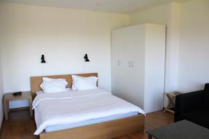a bedroom with a bed with white sheets and a cabinet at Place Lund Studios in Lund