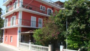 un edificio rojo con balcones y árboles en Dionisis Apartments en Ayia Evfimia