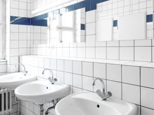 a white tiled bathroom with two sinks and mirrors at Amstel House Hostel in Berlin +32 photos