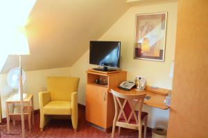 um quarto com uma secretária, uma televisão e uma cadeira em Hotel und Restaurant Eurohof em Duisburg