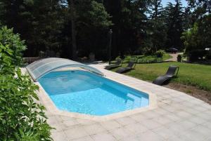 a swimming pool in a yard with chairs around it at la bonbonniere in Saunay