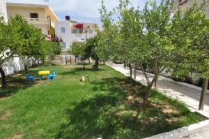 einen Park mit Bäumen und einem Hund im Gras in der Unterkunft Ocean Village Apartments in Agia Pelagia