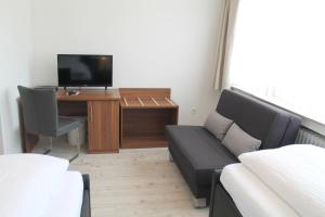 a living room with a couch and a desk with a tv at Haus Kastanienhof in Mülheim an der Ruhr