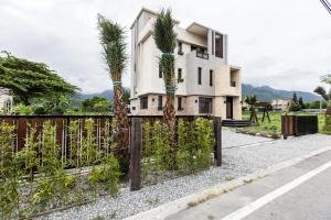 ein Haus mit Palmen vor einem Zaun in der Unterkunft Valley Silence B&B in Jian