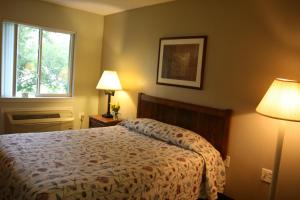 a bedroom with a bed and two lamps and a window at Affordable Suites Jacksonville in Jacksonville