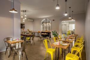 a restaurant with yellow chairs and tables in a room at Urban Garden Hotel in Rome