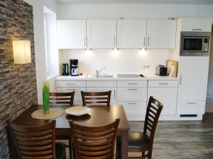 eine Küche mit einem Tisch und Stühlen sowie eine Küche mit weißen Schränken in der Unterkunft Appartementhaus Gutenberg in Binz