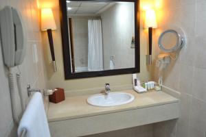 a bathroom with a sink, mirror, and toilet at Khalidiya Hotel in Abu Dhabi
