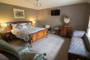 a bedroom with a bed and a chair and a mirror at The Red Pump Inn in Clitheroe