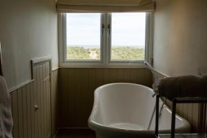 a bathroom with a white tub and a window at The Sail Loft in Southwold