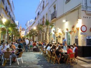 un grupo de personas sentadas en mesas en una calle de la ciudad en Casa Caleta a 2 minutos de la playa, en Cádiz